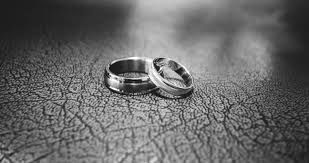 Black and white macro shots of wedding rings on textured surface.