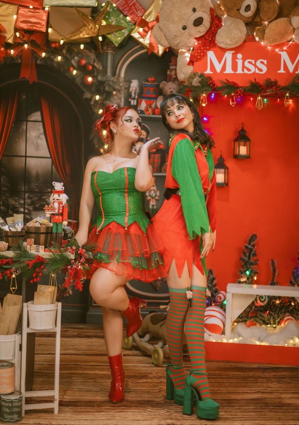 Holiday themed photoshoot with Christmas costumes and decorations against red backdrop.