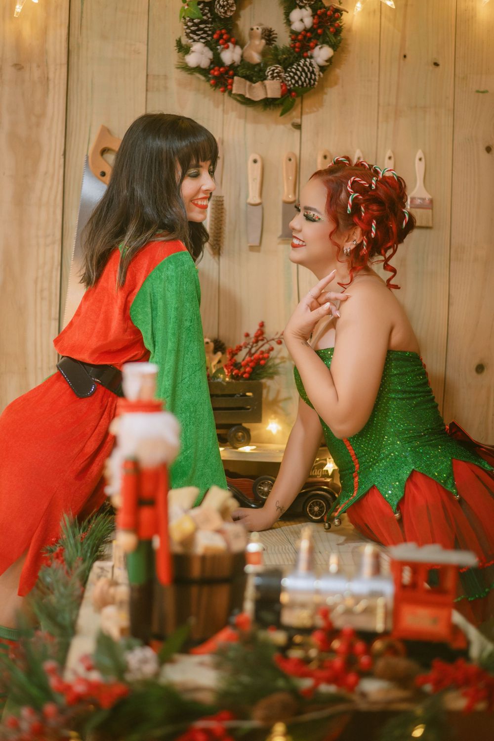 Two festively dressed companions share a joyful moment in front of a holiday wreath and decorations.