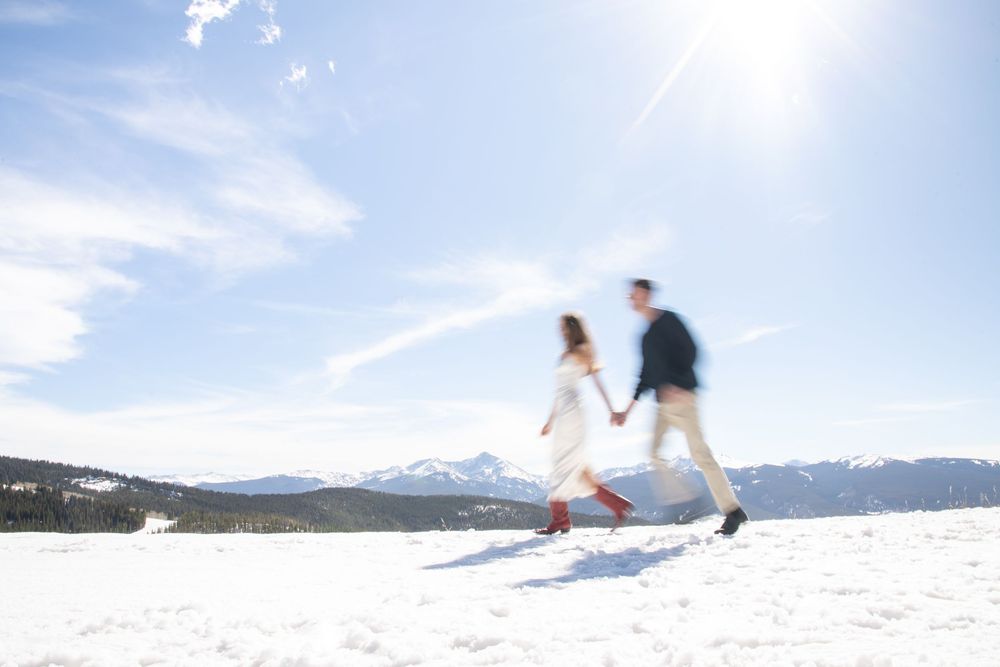 Artistic winter engagement photos on Vail mountain with snow covered mountain peaks in the background
