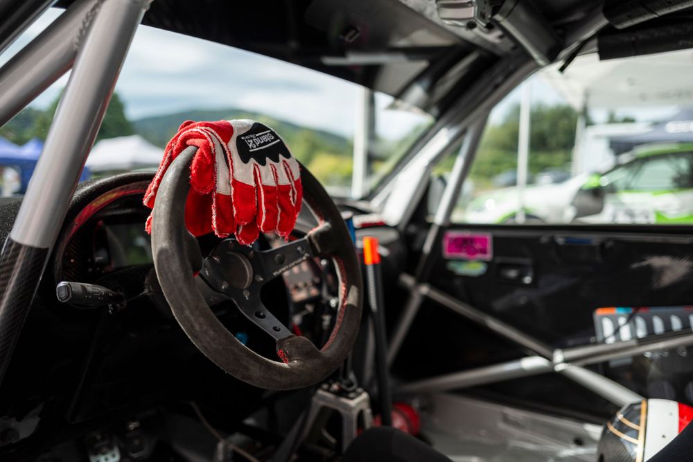 Racing steering wheel with red grips mounted in performance vehicle cockpit.