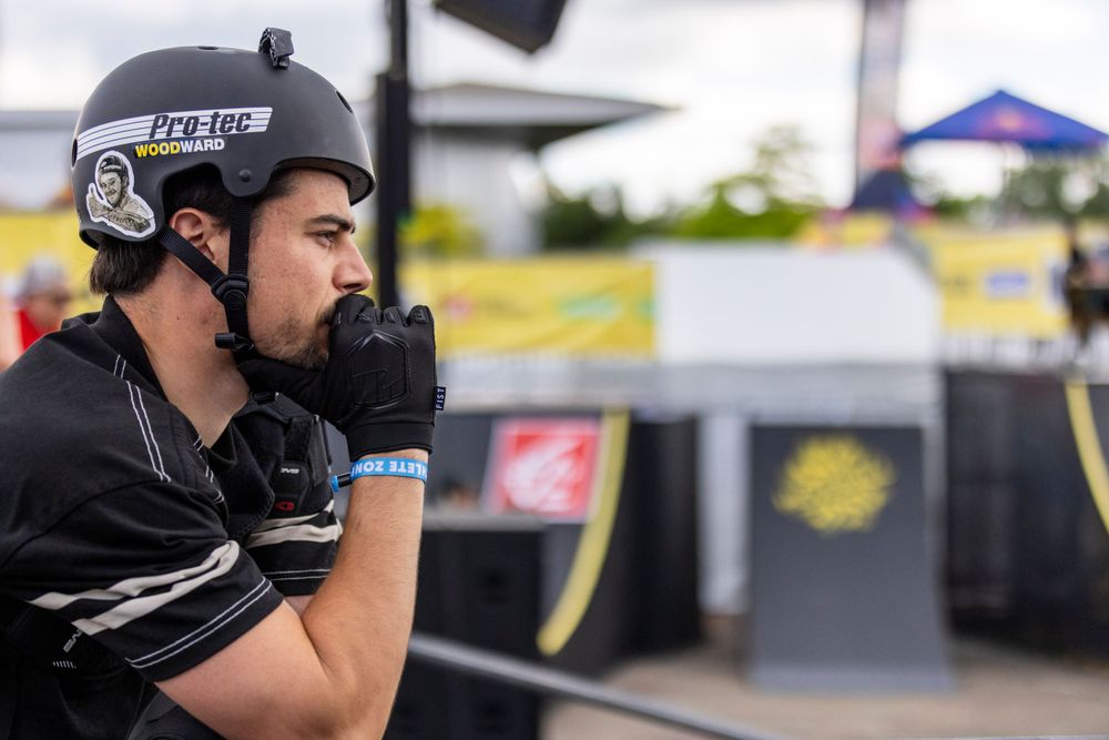 BMX athlete in black helmet and protective gear preparing for performance.
