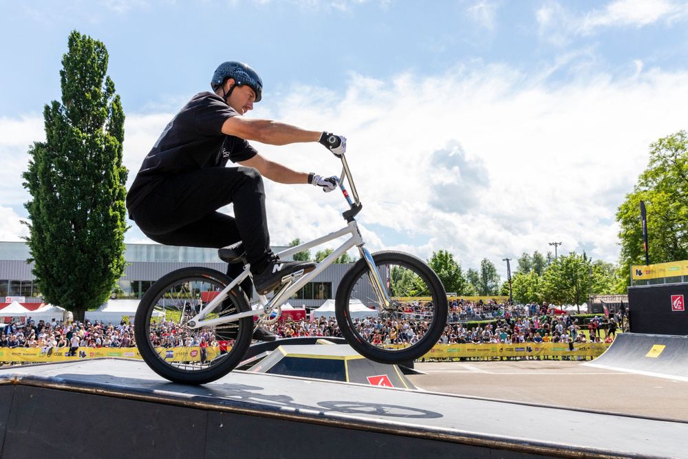 BMX rider performing a trick on a ramp against a blue sky.