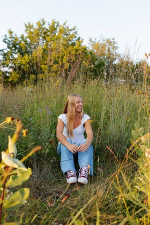 Natural outdoor portrait session in tall grass during golden hour.