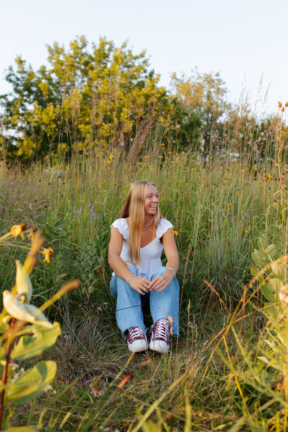 Natural outdoor portrait session in tall grass during golden hour.
