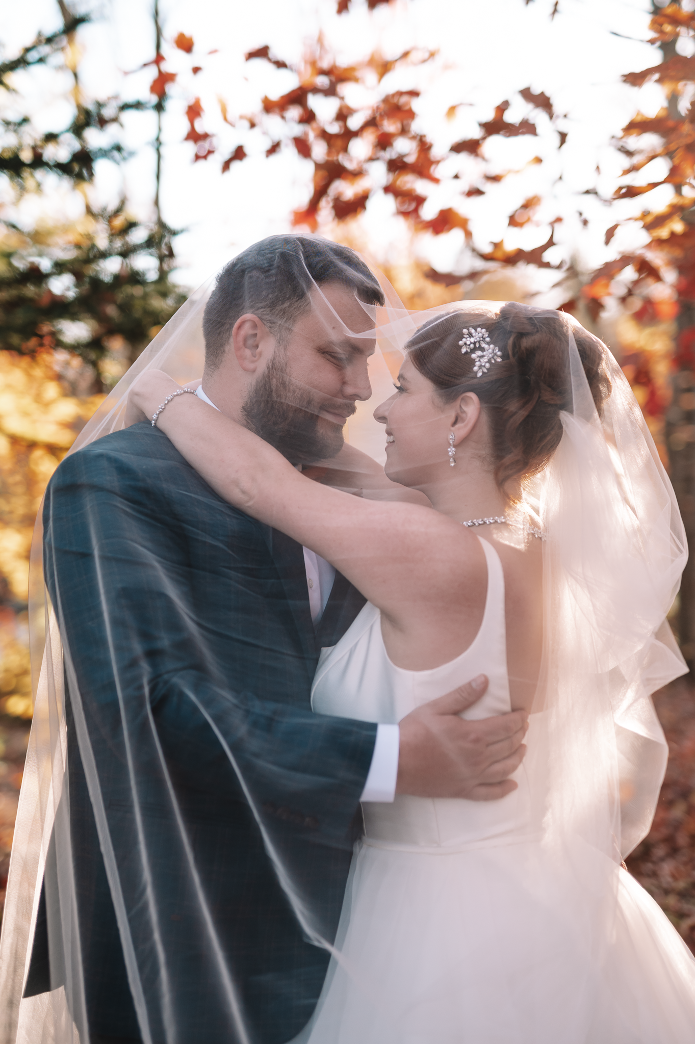 Couple walks along lakeside path in wedding attire during sunset photo session.