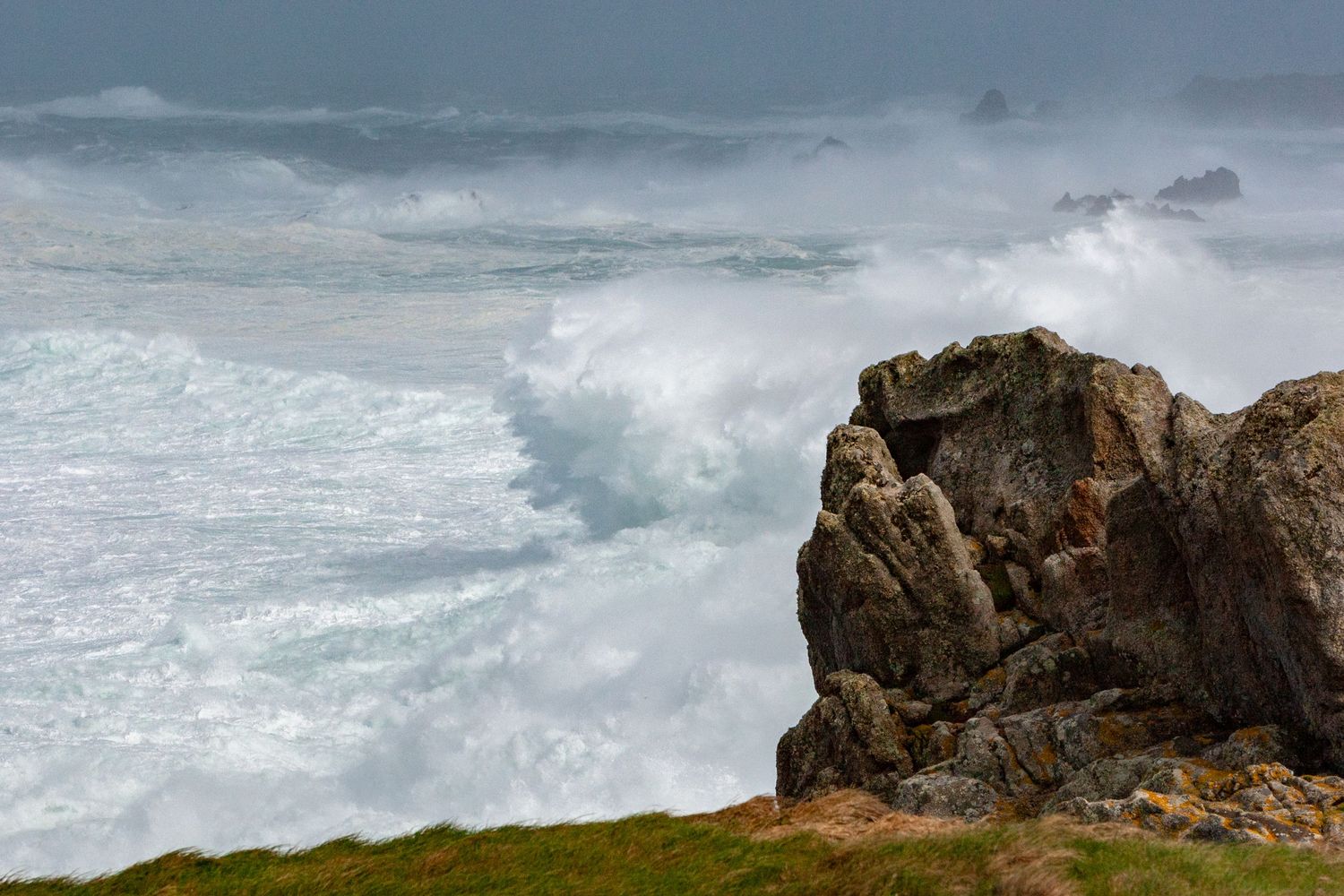 Powerful waves crash against rugged coastal cliffs during stormy weather at sea.