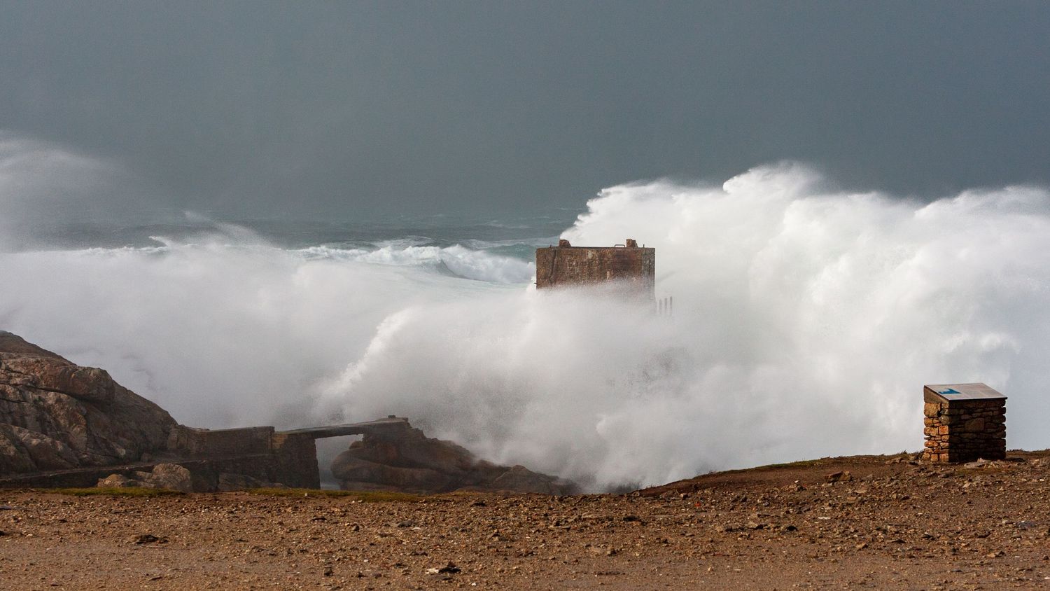 Massive wave engulfs coastal building during intense storm surge.