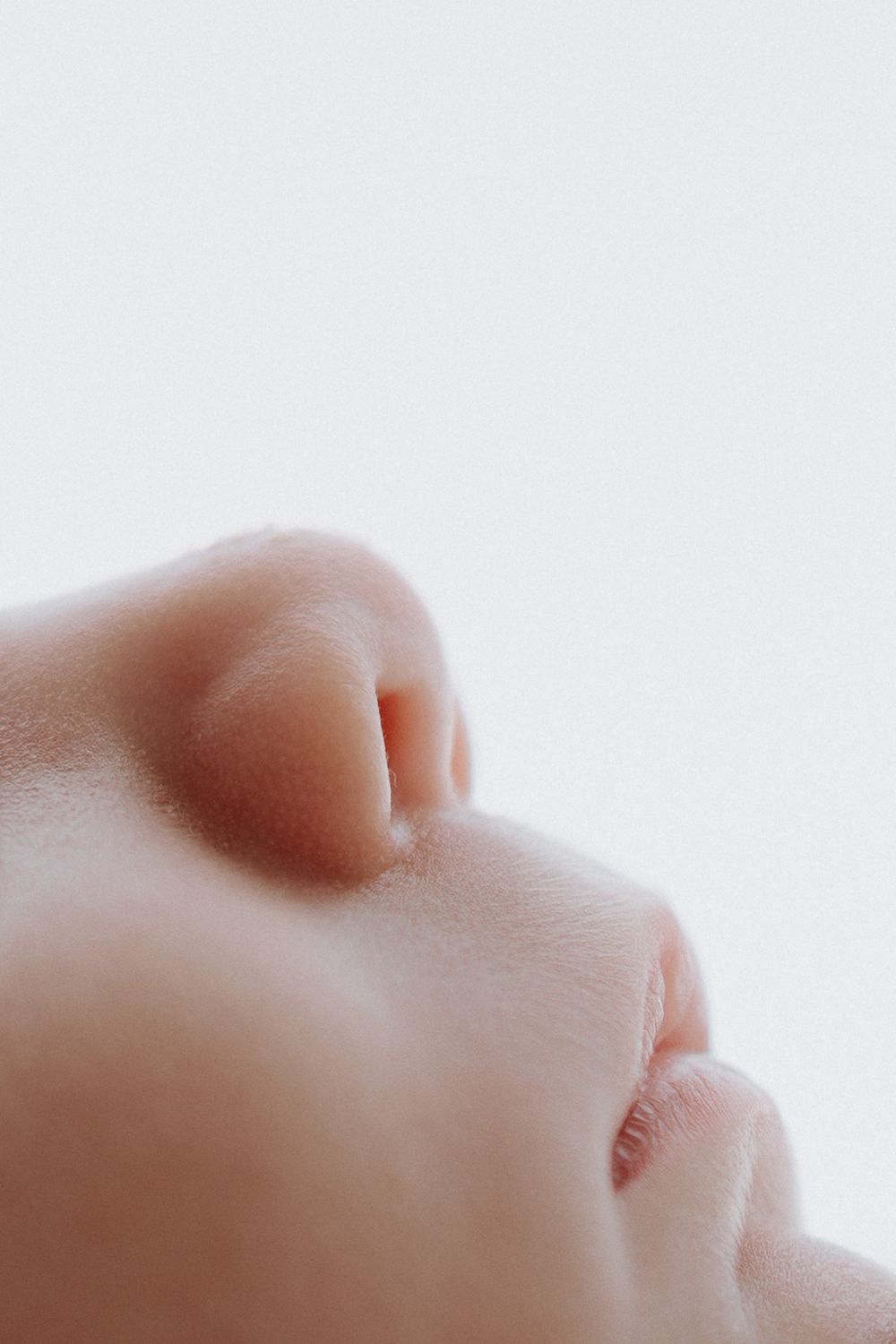 Close-up profile view of a sleeping baby's face against a white background.