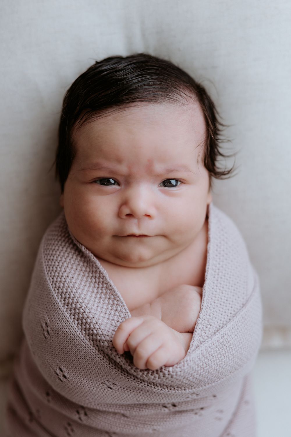 A series of newborn baby portraits showing close-up views wrapped in soft pink knit blanket.