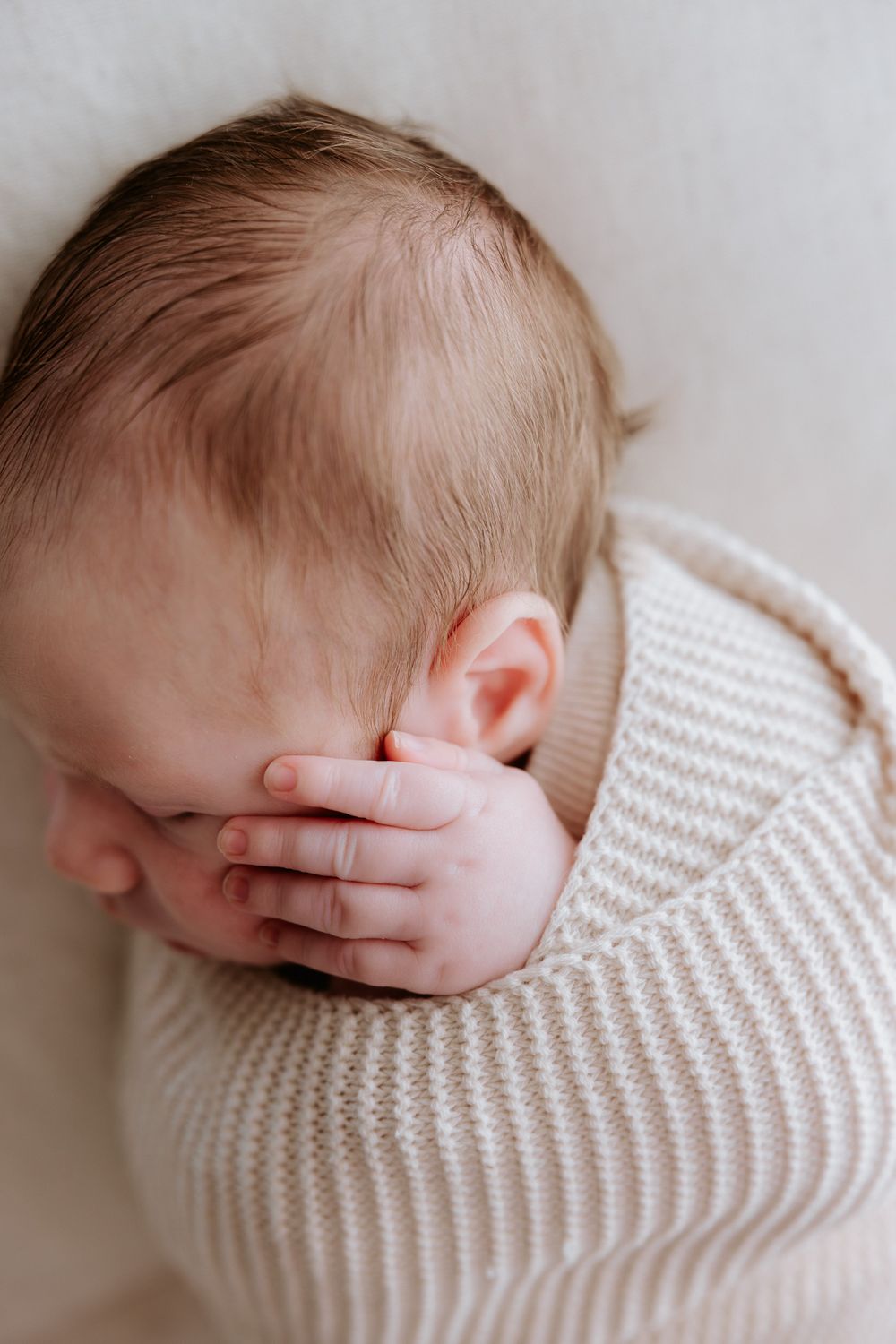 A series of soft, minimalist photos showing a sleeping baby wrapped in a white knit blanket.