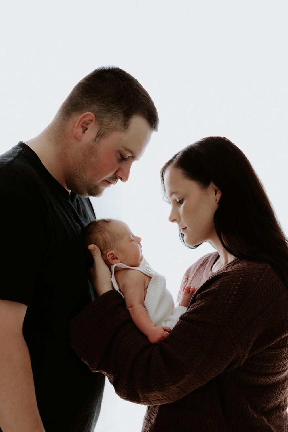 A series of intimate family portraits showing tender moments between parents and baby against a light background.