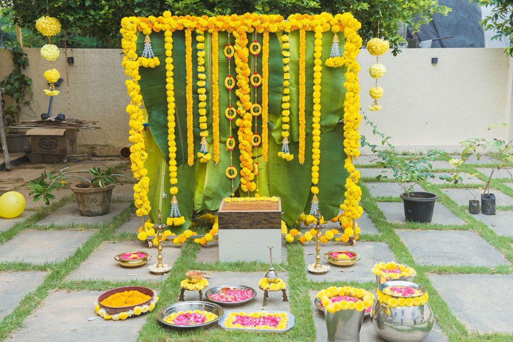 Yellow marigold flower decorations and traditional food items arranged for an Indian ceremony.