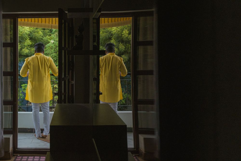 A silhouette of someone wearing yellow standing in a doorway looking outside.