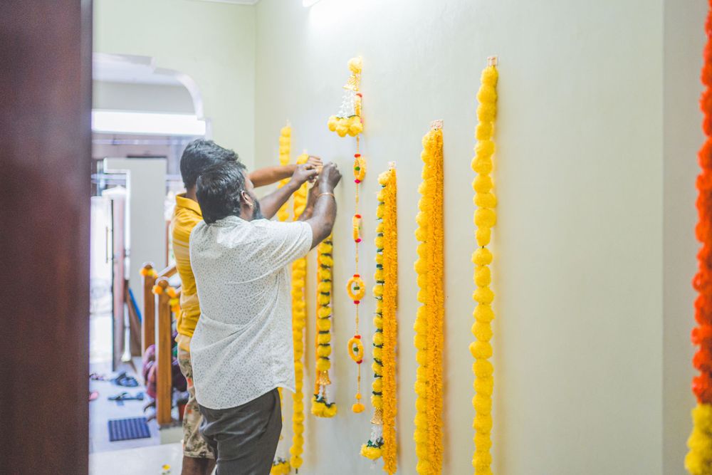 Person hanging yellow marigold garlands on wall for traditional decoration.