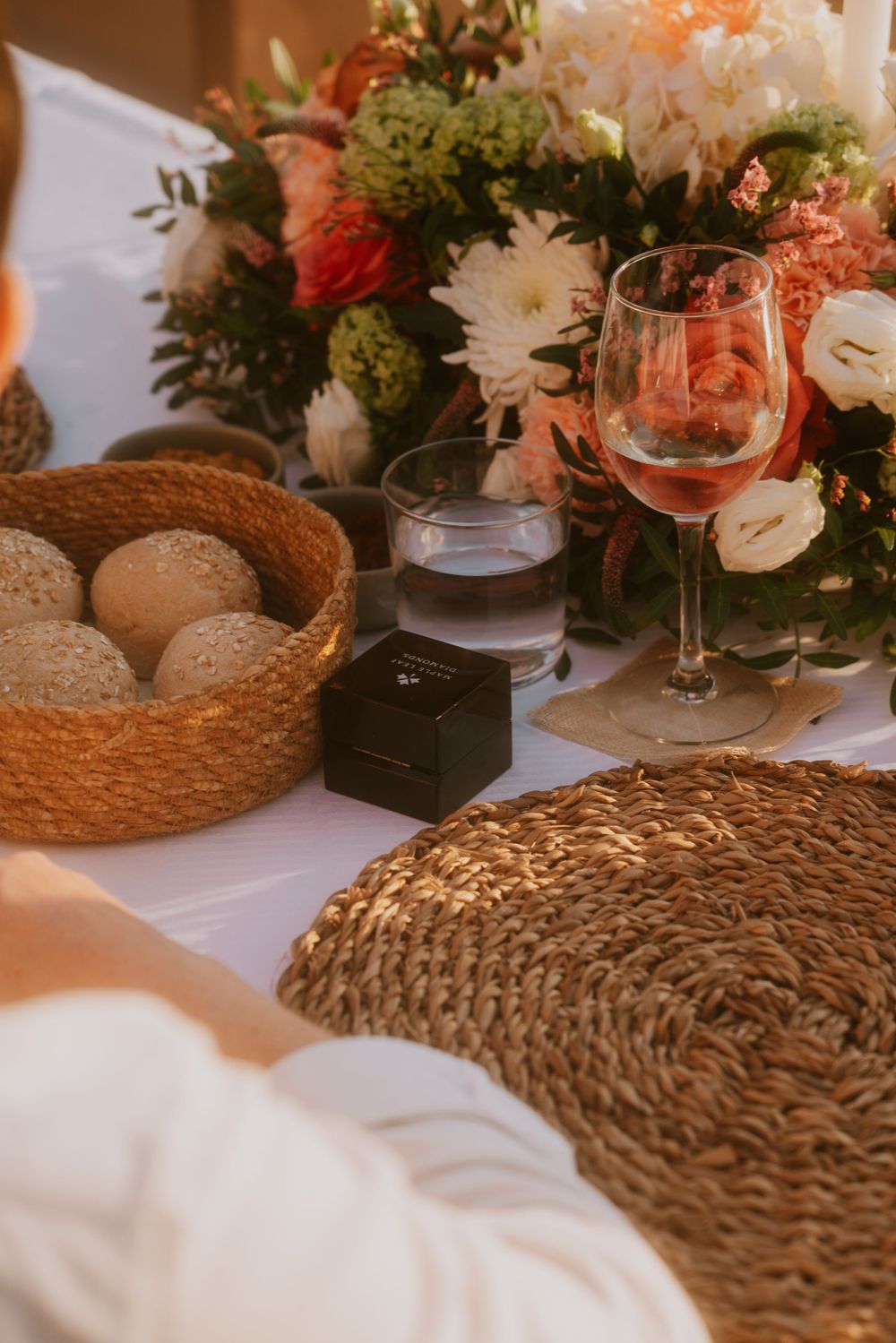 Elegant table setting with floral centerpiece, bread basket, and wine glass.