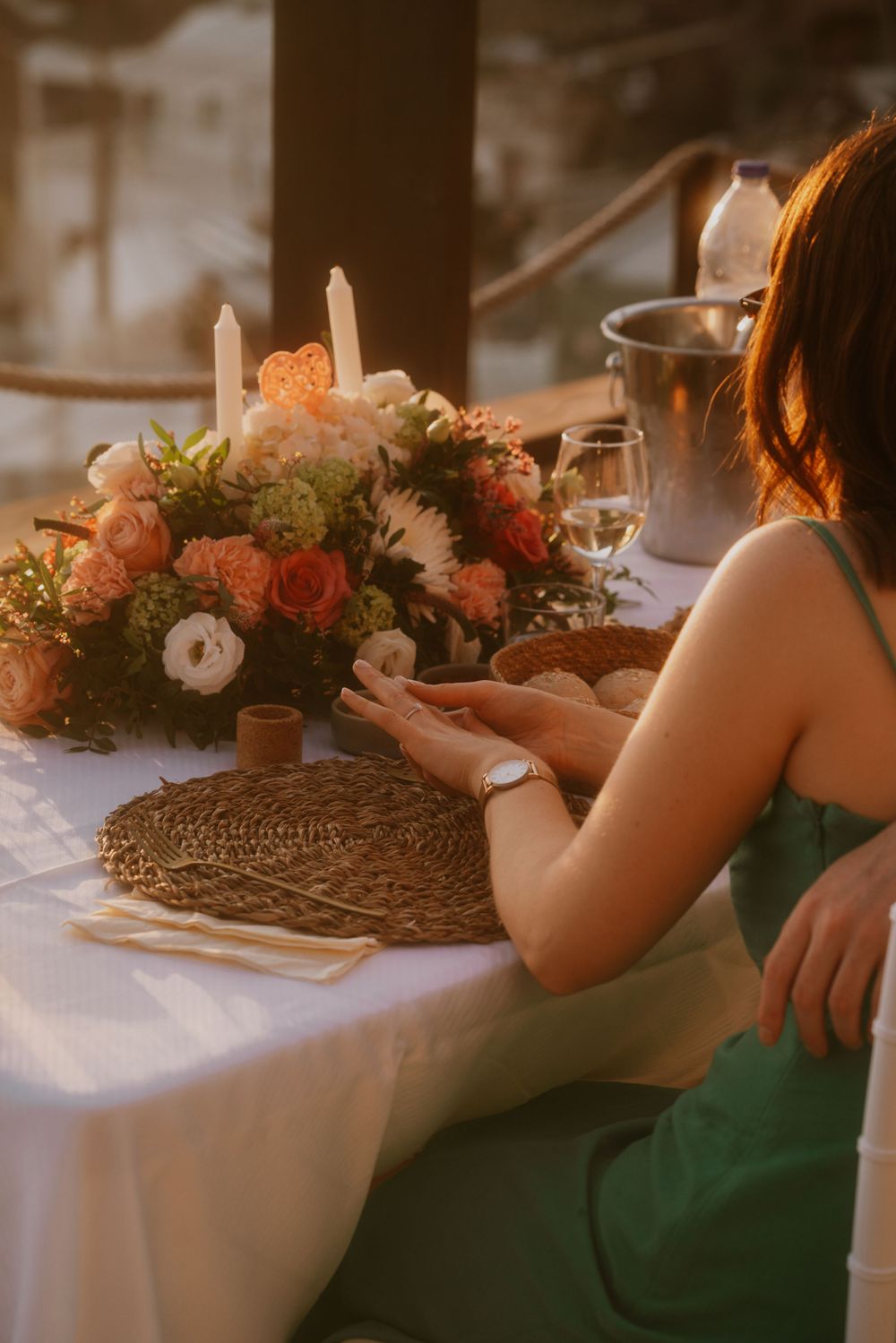 Romantic dinner setup with coral and white floral arrangement and woven placemats.