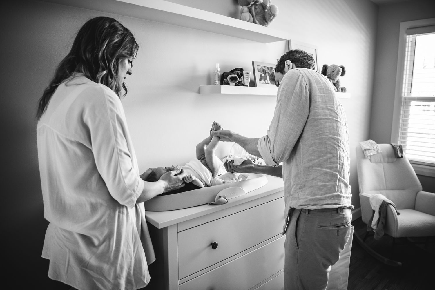 BW image of a newborn getting their diaper changed by mom and dad.