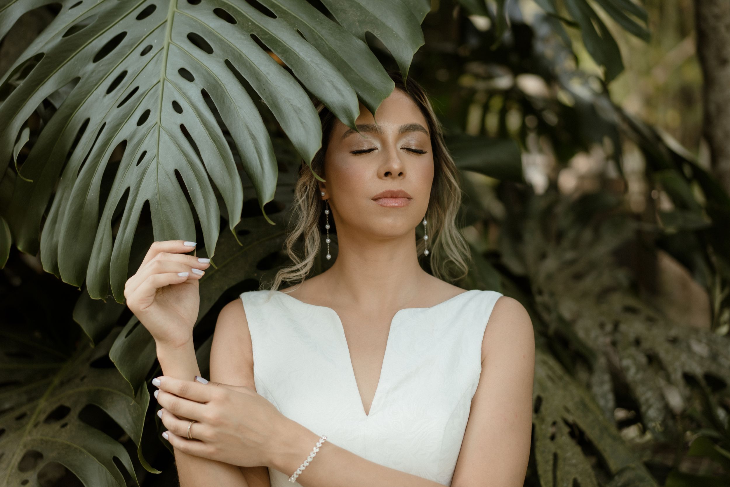 Serene tropical wedding portrait set against lush monstera palm leaves in dappled sunlight.