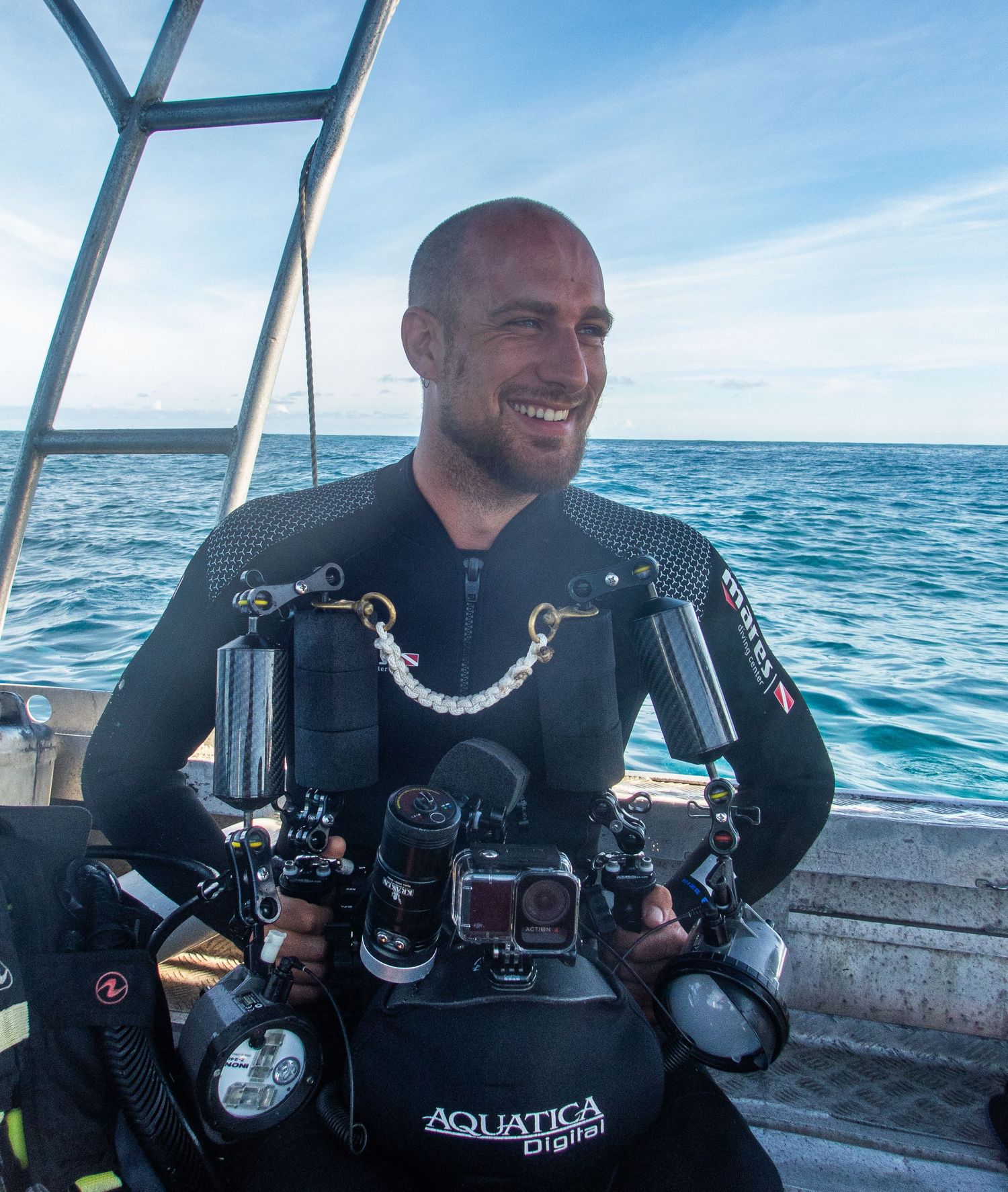 Scuba diver with professional underwater camera equipment aboard marine vessel.