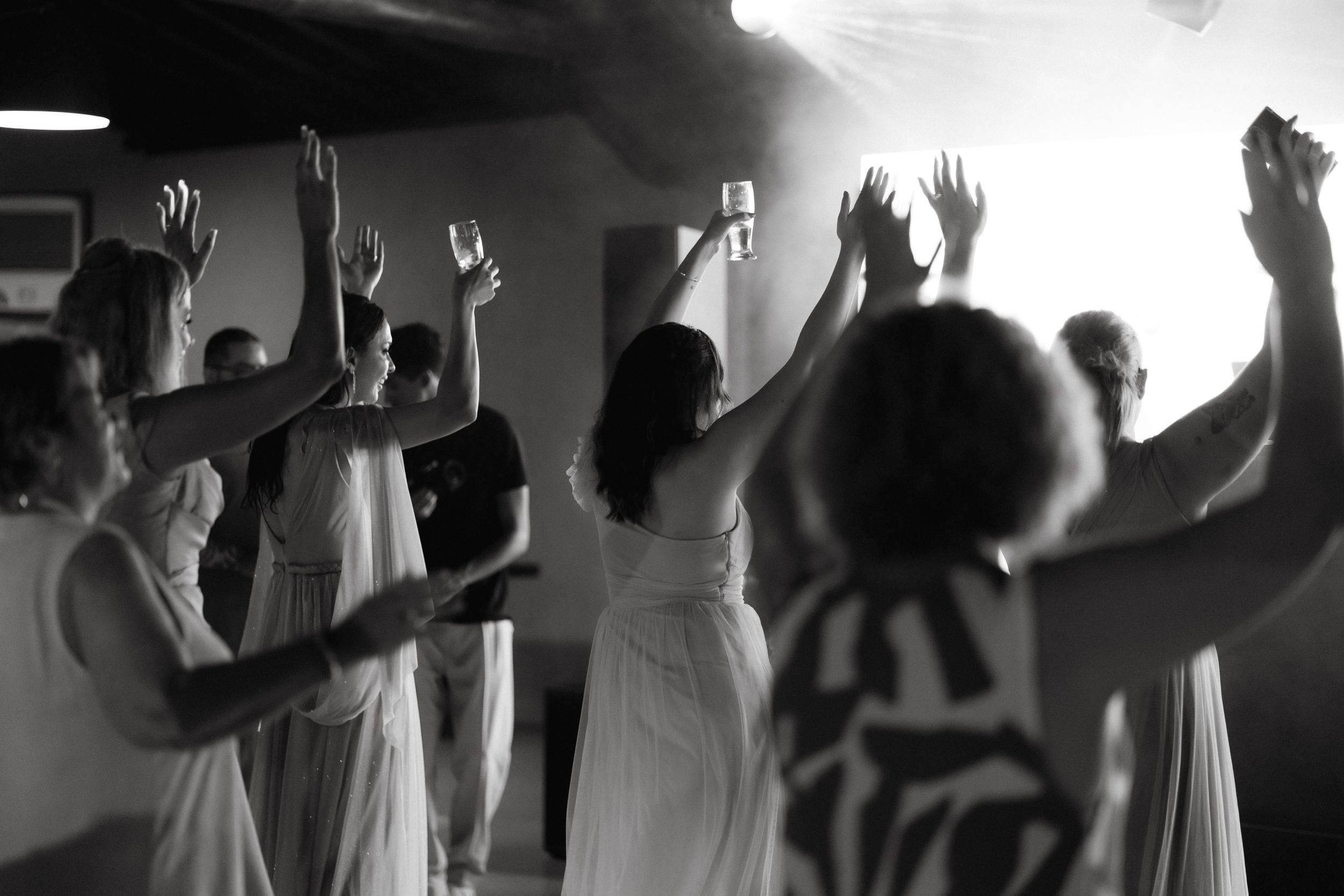 Silhouetted dancers with raised hands in black and white photography.
