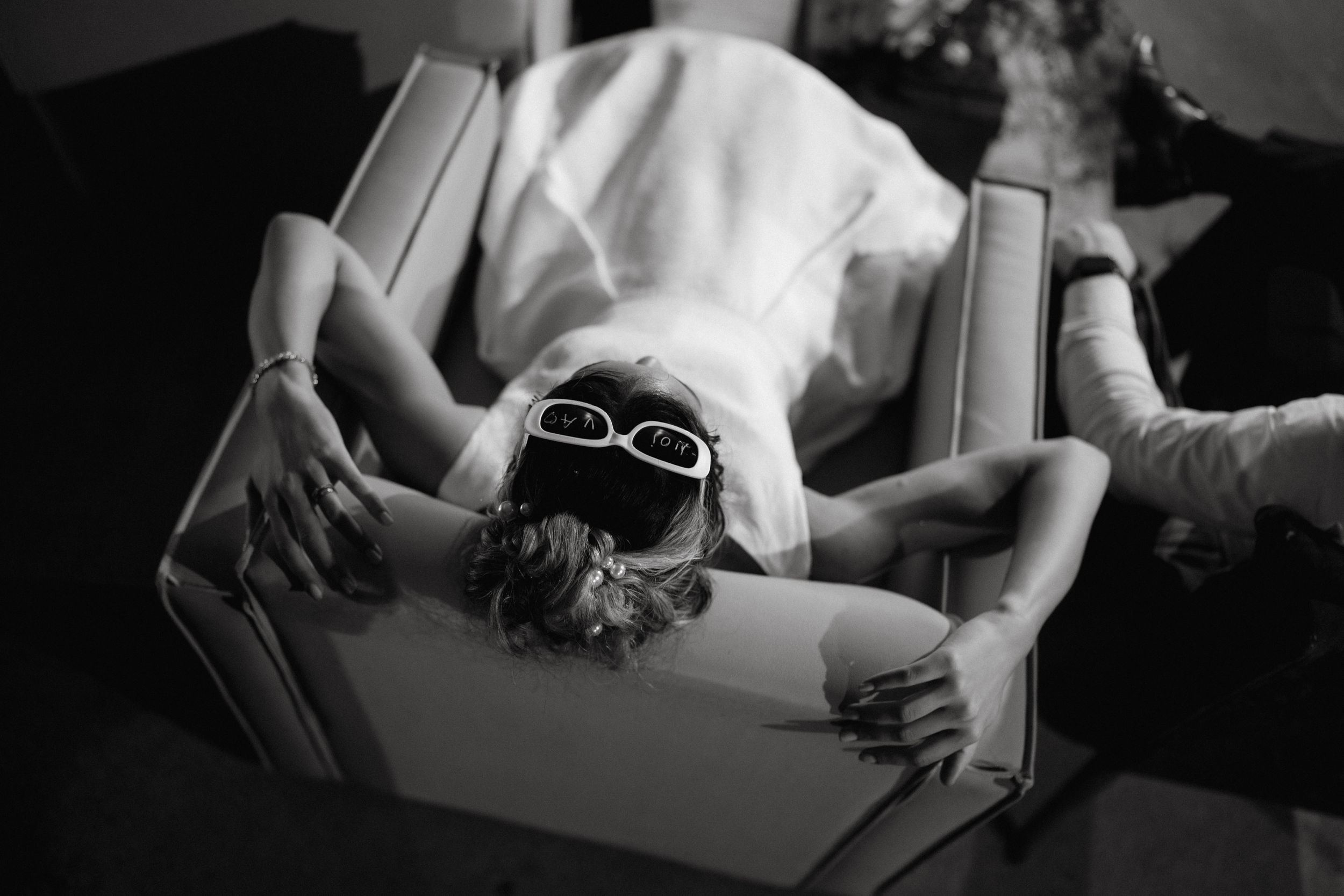 Artistic black and white photo of a dancer reclining with sunglasses.