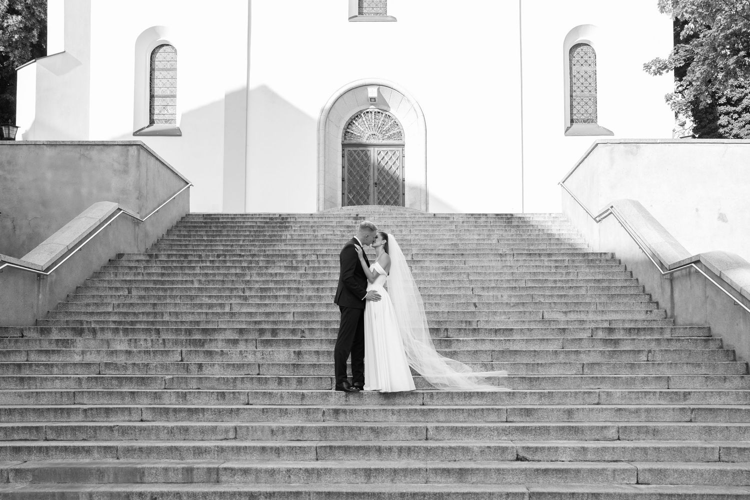 Intimate wedding portrait with white floral bouquet against neutral background.