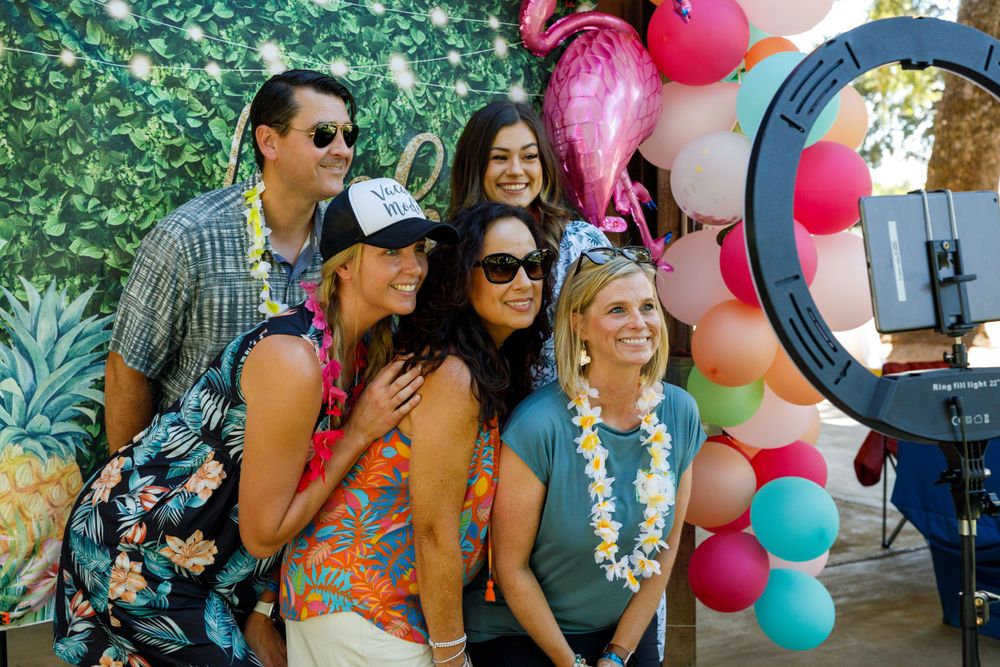 Group poses together for photos in front of a balloon arch and greenery backdrop.