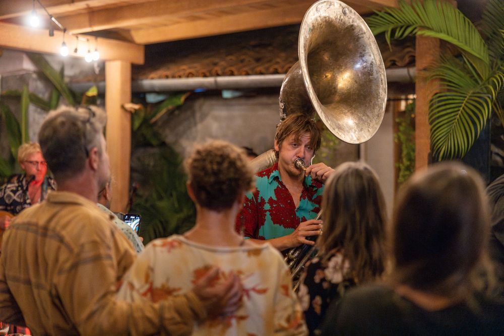 Musicians perform with a vintage gramophone at a rustic outdoor gathering.