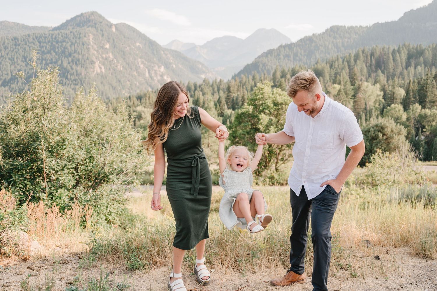 Playful family moment captured in a mountain meadow during golden hour.