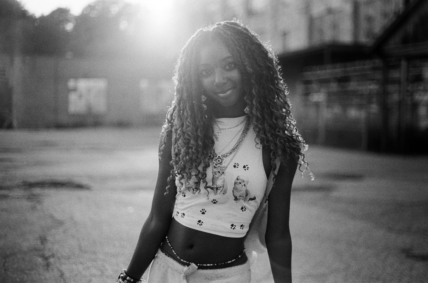 Artistic black and white portrait with dramatic sunlight and urban backdrop.
