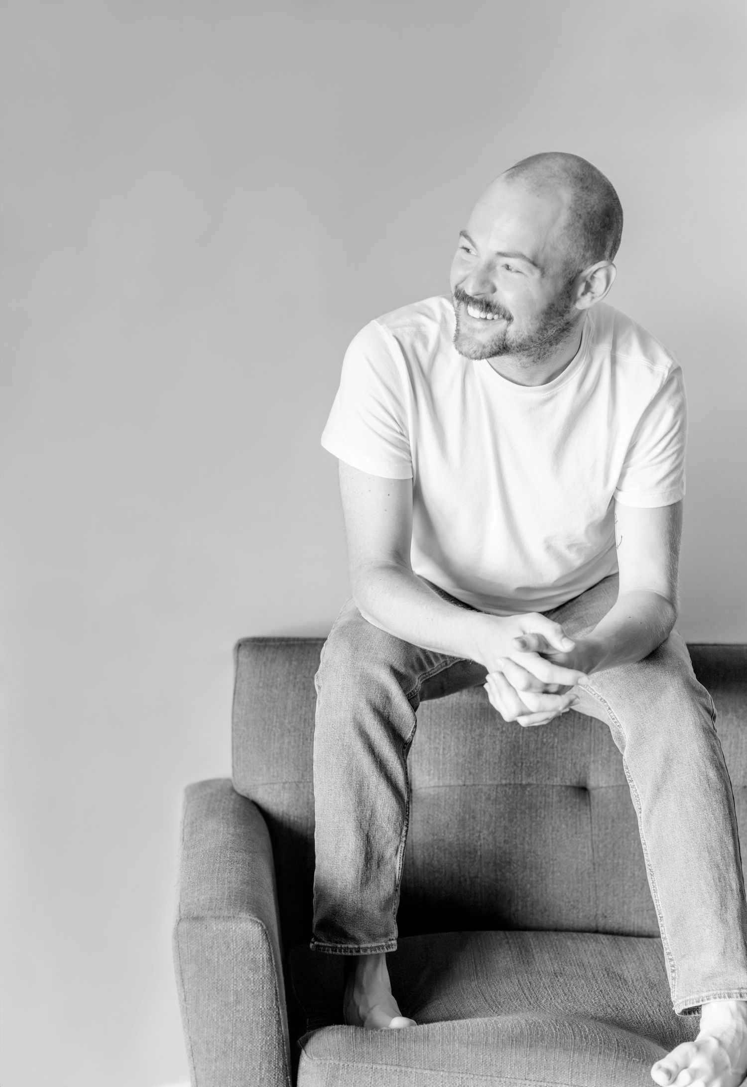 Self-portrait of a male photographer smiling while holding a Nikon camera.