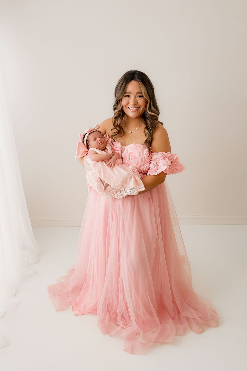 Beautiful mother holding newborn baby in matching pink gowns during studio portrait session in Summerville SC