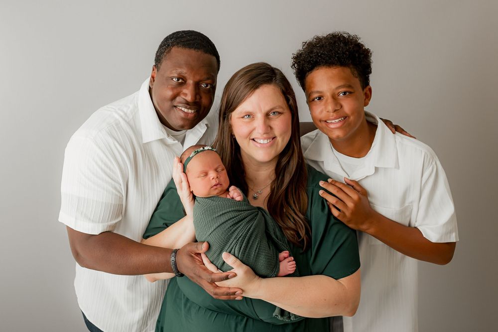 Family of four with newborn baby in green wrap during studio portrait session in Summerville SC