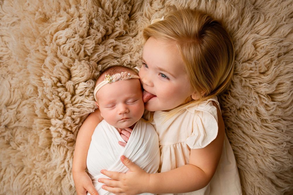 Sweet sibling portrait with newborn baby in cream wrap and big sister on textured flokati blanket in Summerville SC