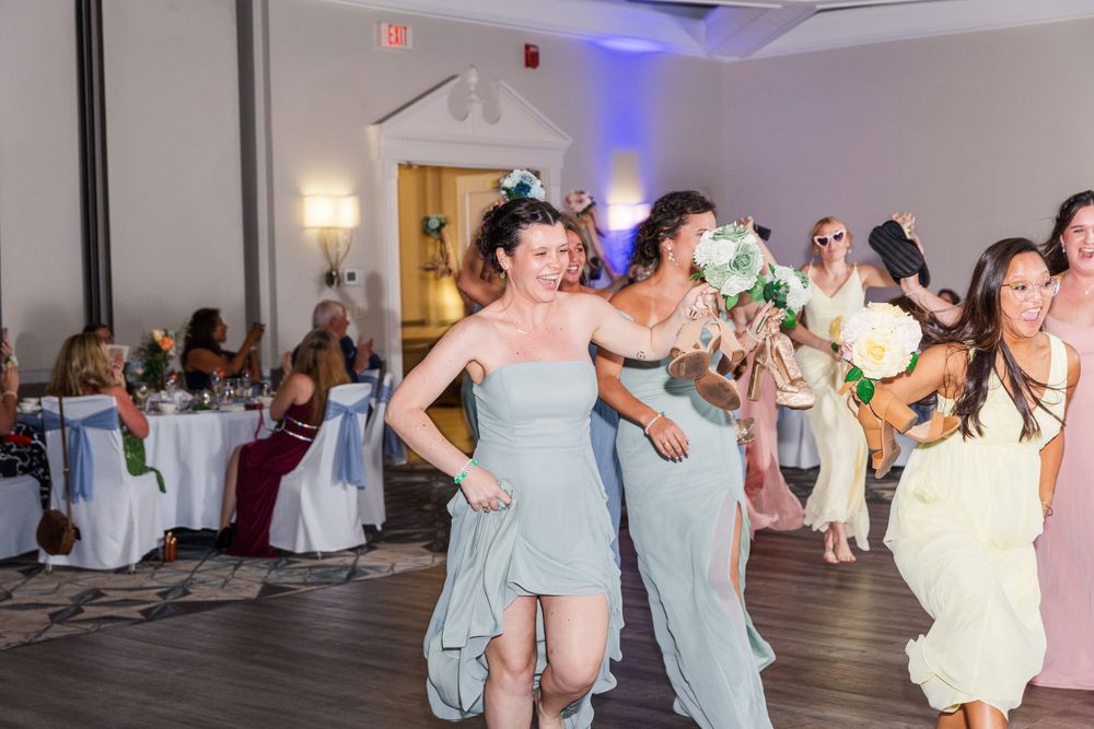 Wedding reception dance floor filled with people in formal attire celebrating.