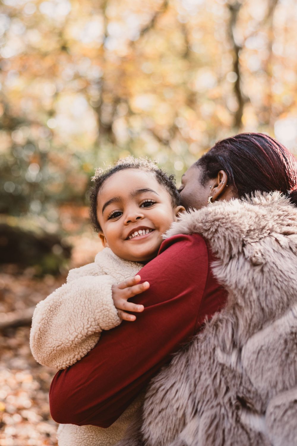 Tender autumn moment captured outdoors with warm embraces and joyful smiles among fallen leaves.