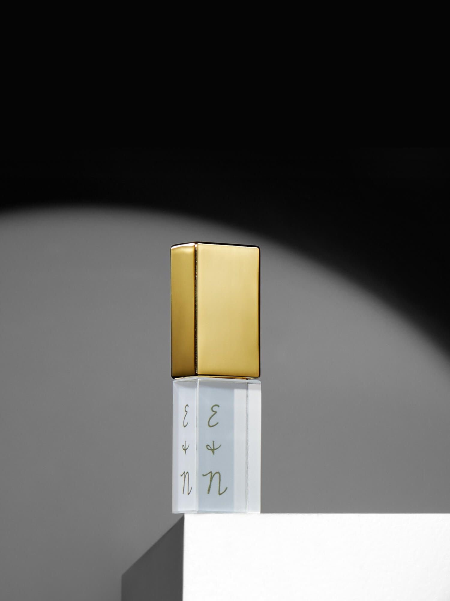 A luxury gold-capped perfume bottle stands elegantly against a dark background with dramatic lighting.