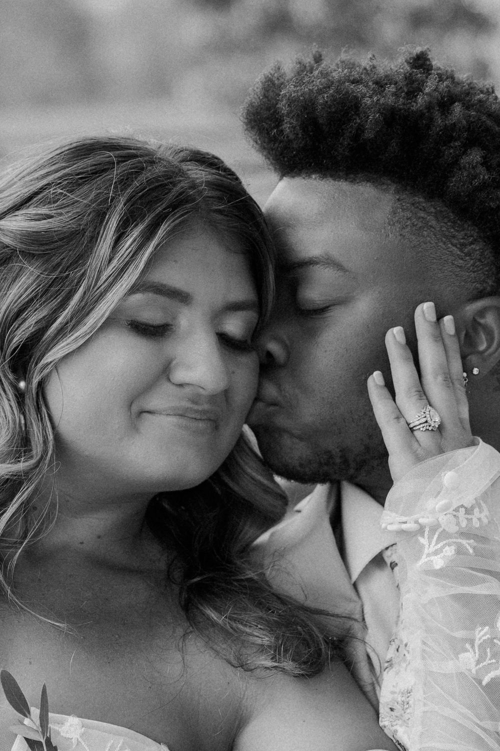 A romantic black and white close-up portrait of a couple sharing an intimate moment in wedding attire.