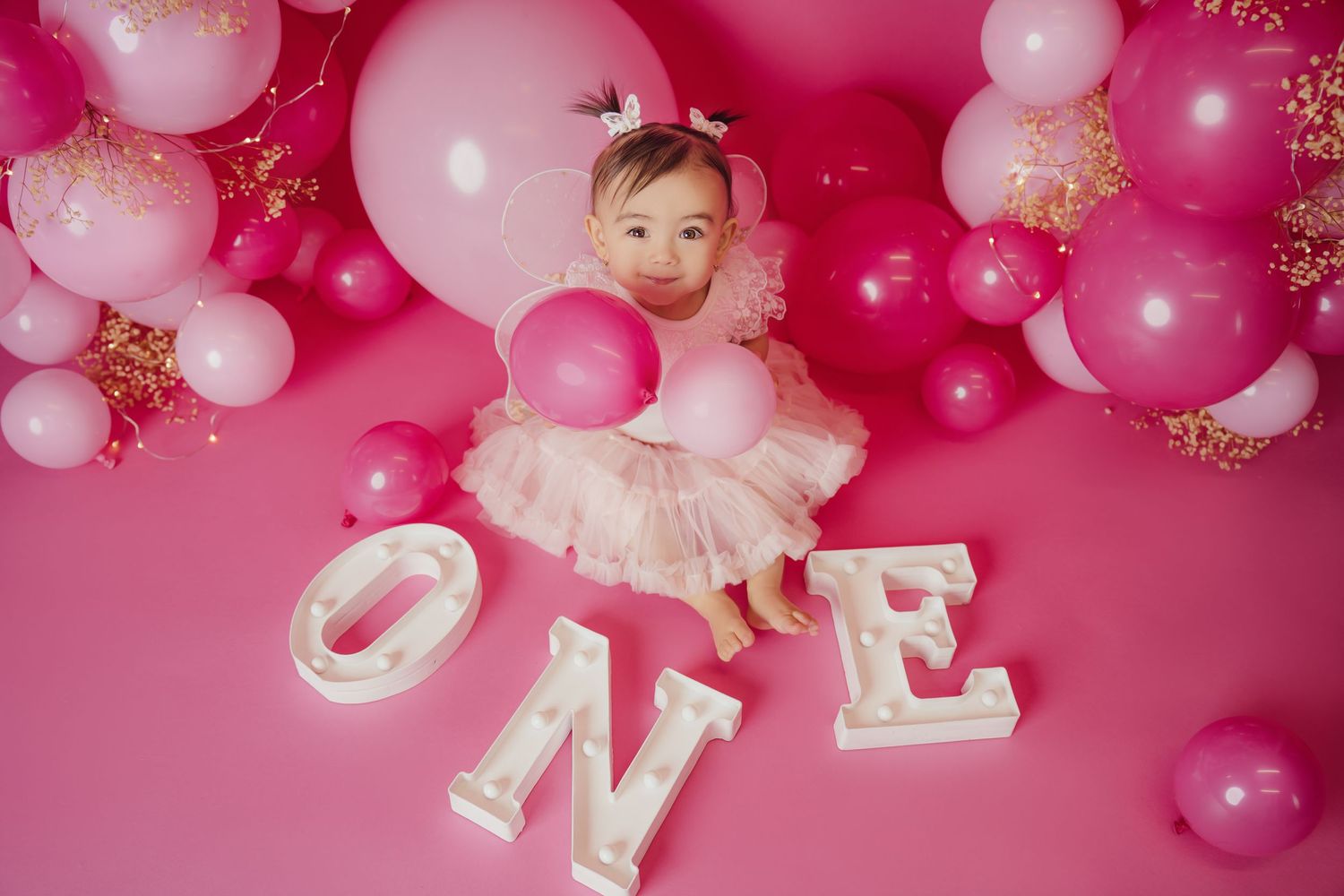 A joyful cake smash session featuring a baby laughing and playing with a colorful cake, surrounded by festive decoration