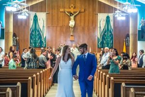 Church wedding ceremony in progress with wooden pews and stained glass windows visible.