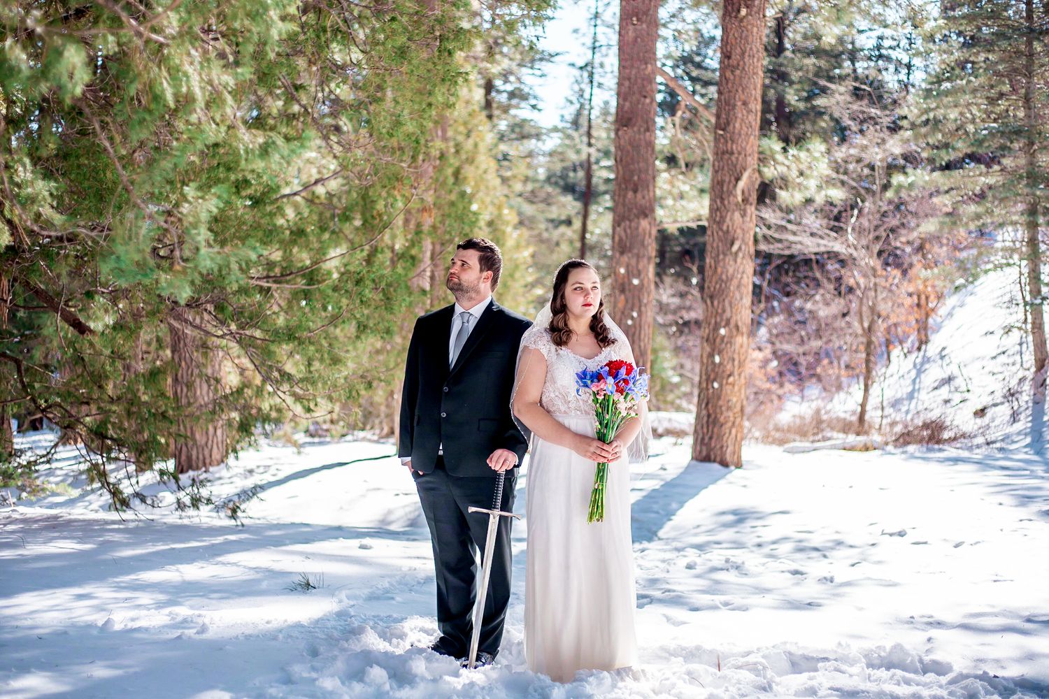 A winter wedding photo shows a couple standing together in a snow-covered forest setting.