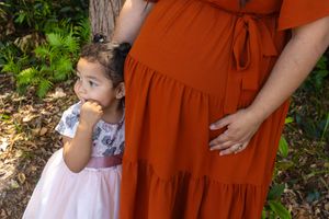 Close-up shot of a sweet moment between mother and child in contrasting orange and pink dresses.