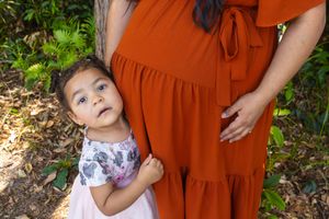 A candid moment captured between parent and child against a rust-colored dress.
