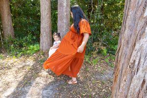 A playful outdoor photoshoot among tall trees with contrasting dress colors.