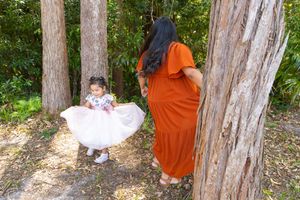 Playful sequence of poses between two figures in orange and white dresses against a woodland backdrop.