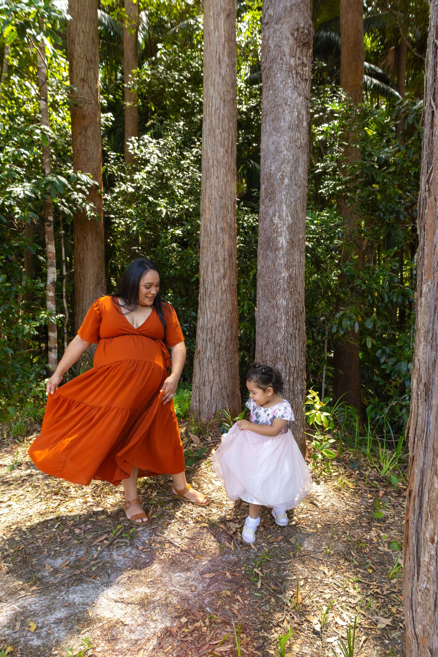 Sequential forest photography showing movement and dance between two figures in contrasting dresses.