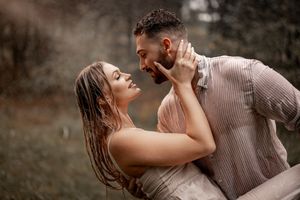Passionate embrace photographed in dramatic rainy weather with natural backdrop.