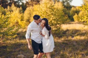 Couple walking together in a golden autumn field during sunset.