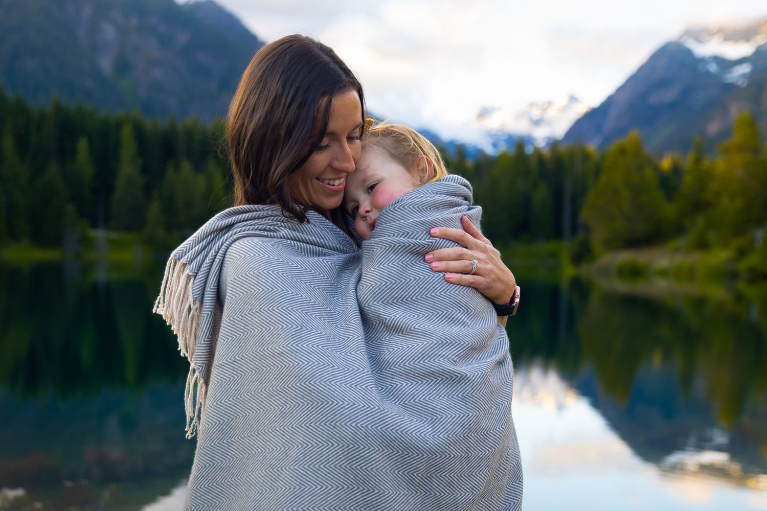 Mom wraps her toddler in a blanket to keep warm during a family photo session at Gold Creek Pond.